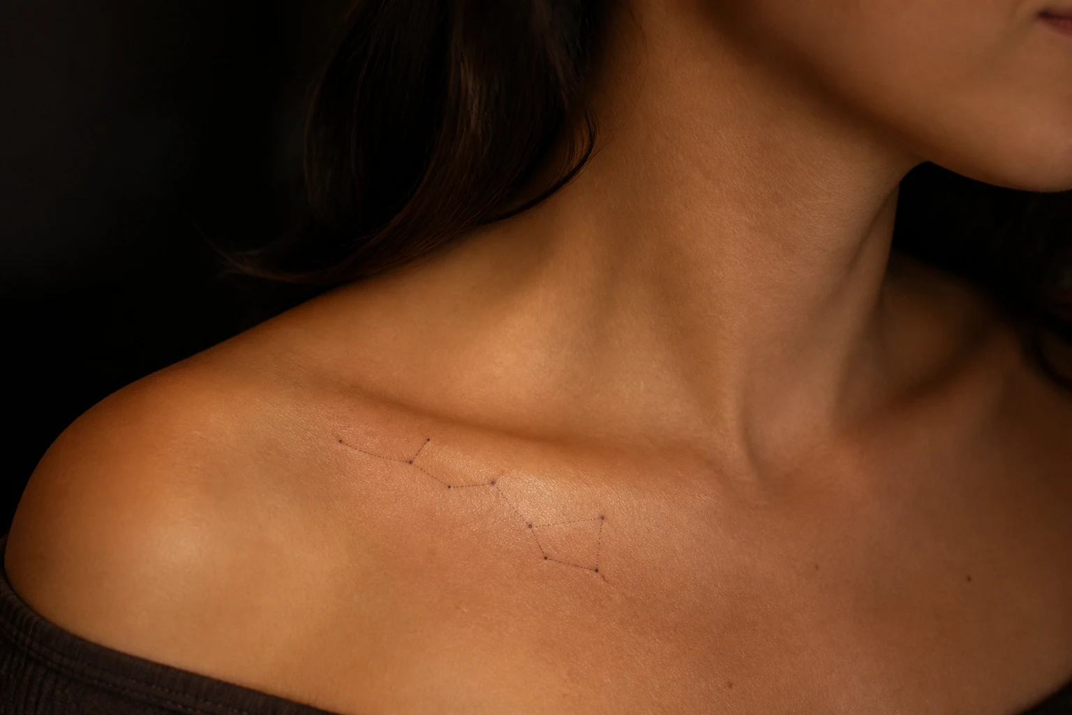 Tatuagem fine-line de constelação fina ligando pequenas estrelas sobre a clavícula, traço delicado